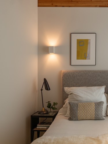 Plaster wall light on one side of the bed